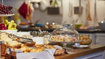 A buffet with various food items including fruits, pastries, and bread.