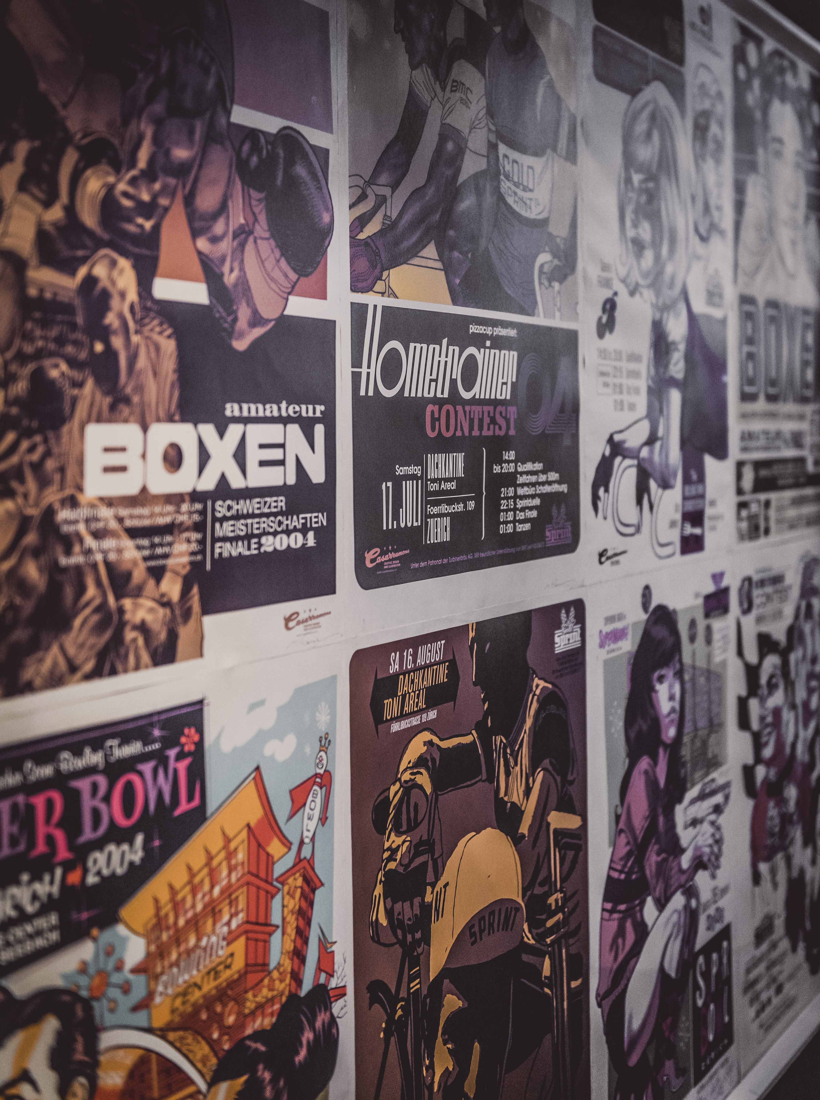 Un mur recouvert de divers affiches et prospectus, dont un pour un événement de boxe et un autre pour un concours d’appareils électroménagers.