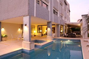 Una piscina al aire libre, sillones reclinables de piscina