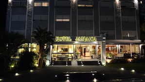 Un hotel llamado "HOTEL JAMAICA" con una entrada bien iluminada, zona de estar al aire libre y fachada de piedra.