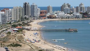 Un paisaje urbano costero con edificios altos, una playa y un muelle.