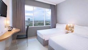 Habitación de hotel con dos camas, un escritorio con silla, televisión y ventana con vista a la ciudad.