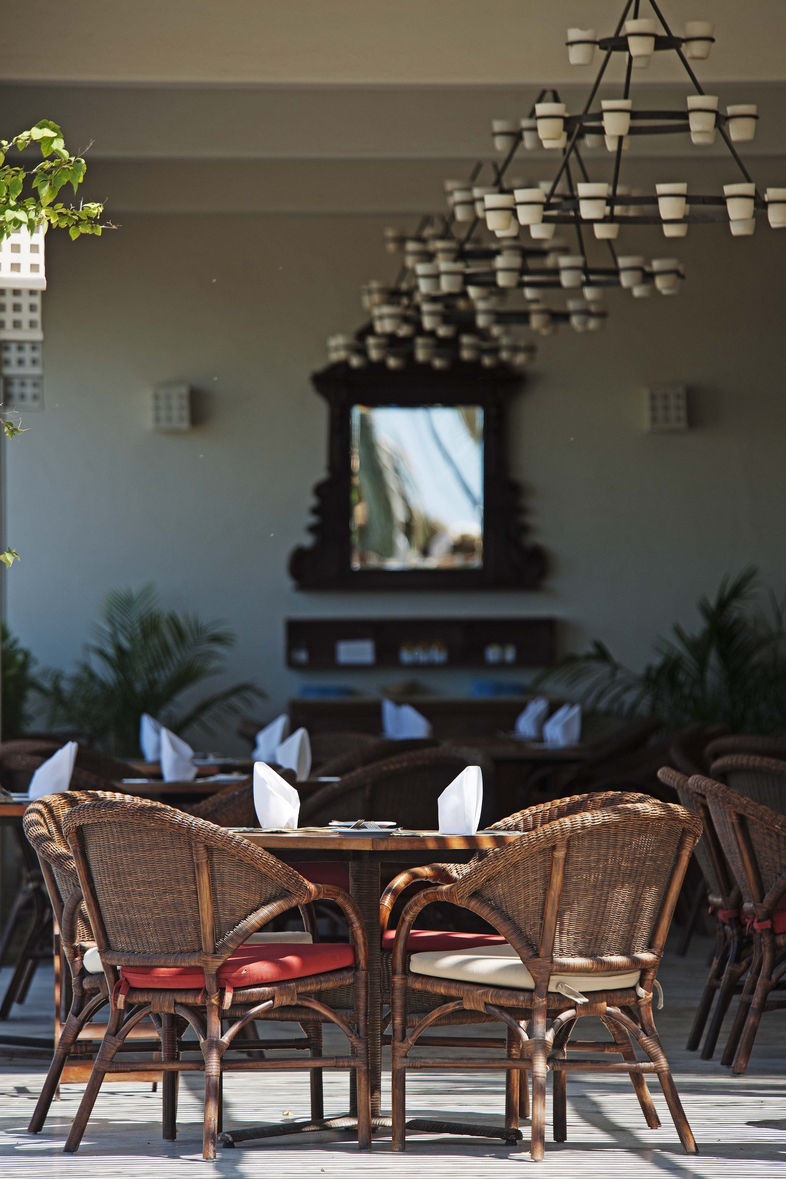 A dining area with wicker chairs and a table, a hanging light fixture, and a television in the background.