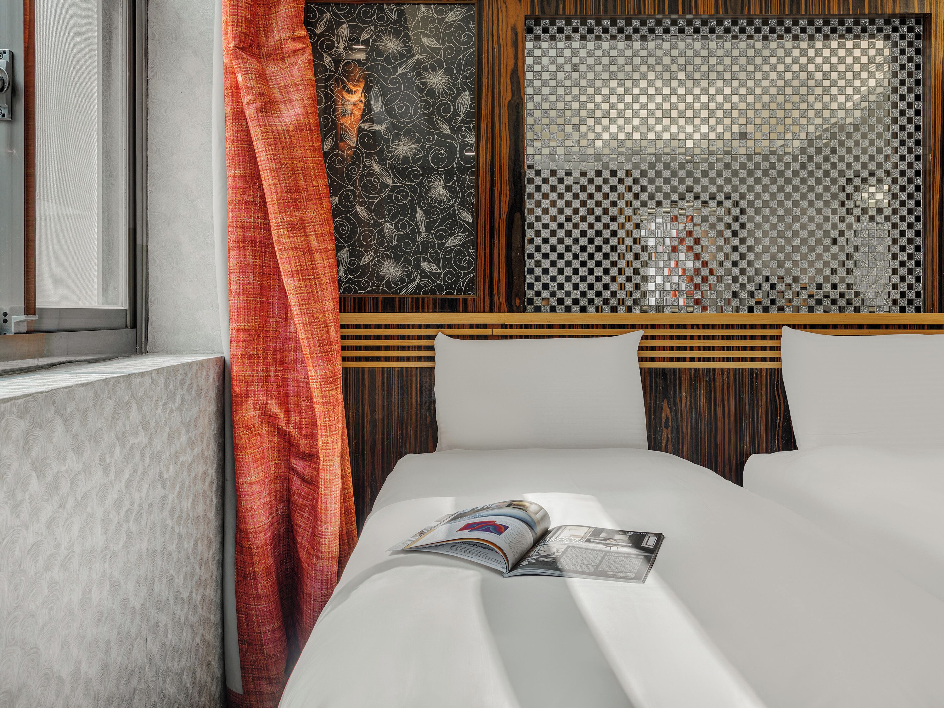 Quarto de hotel com cama, janela com vista e um painel decorativo na parede.