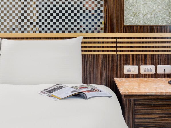 A hotel room with a bed, a nightstand, and a wall with a checkered pattern and a decorative panel.