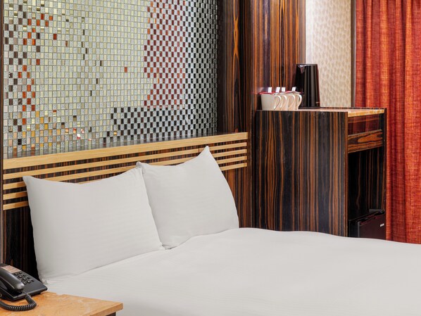 A hotel room with a bed, a bedside telephone, a small table with a cup and saucer, and a wall with a mosaic pattern. - Guide Hotel Taipei Xinyi (Taipei)