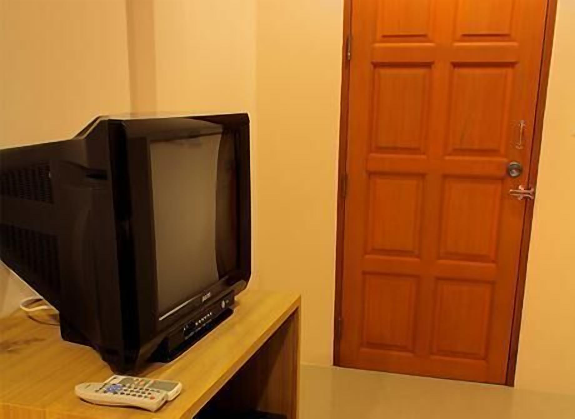 A television on a wooden stand in a room with a wooden door.