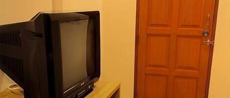 A television on a wooden stand in a room with a wooden door.