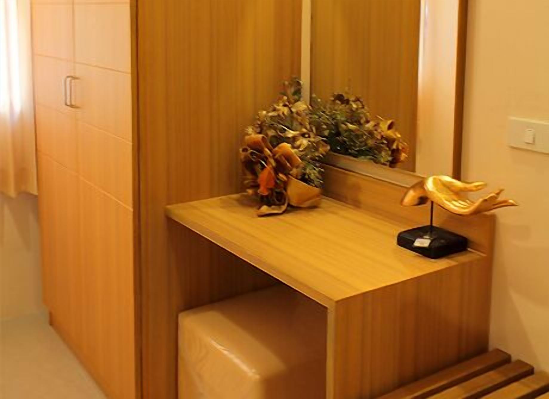 Un tocador de madera con espejo, una planta pequeña y una escultura decorativa.
