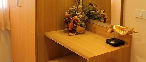 Un tocador de madera con espejo, una planta pequeña y una escultura decorativa.