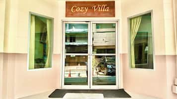 A building entrance with a sign reading 'Cozy Villa' above a set of double doors.