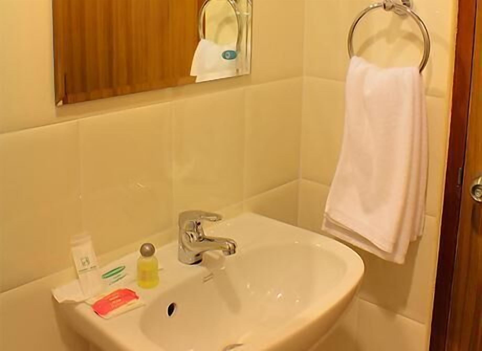 A bathroom with a sink, a mirror, and a towel hanging on a rack.