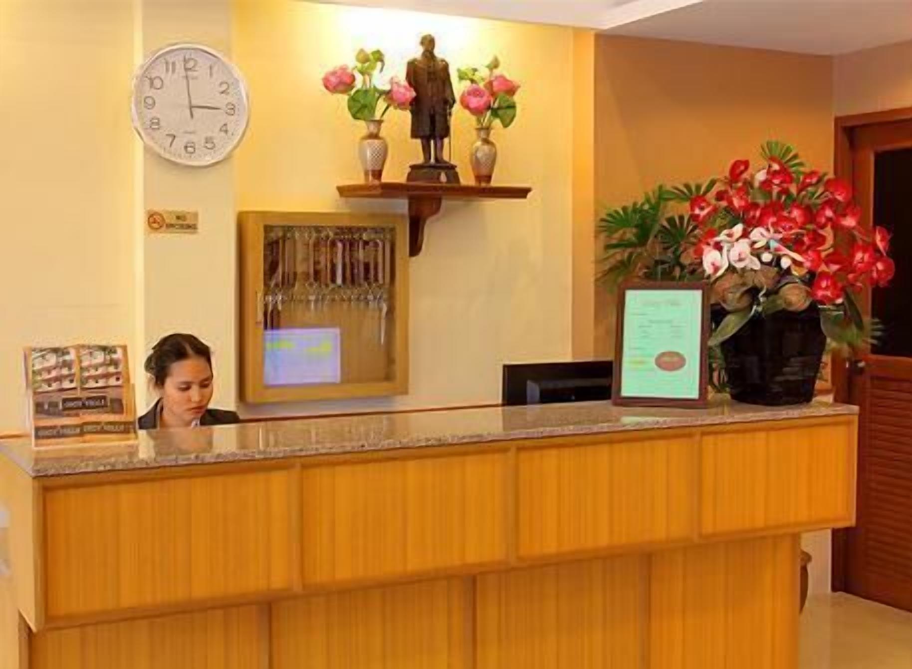 Un mostrador de recepción con un reloj, un perchero para llaves y adornos florales.