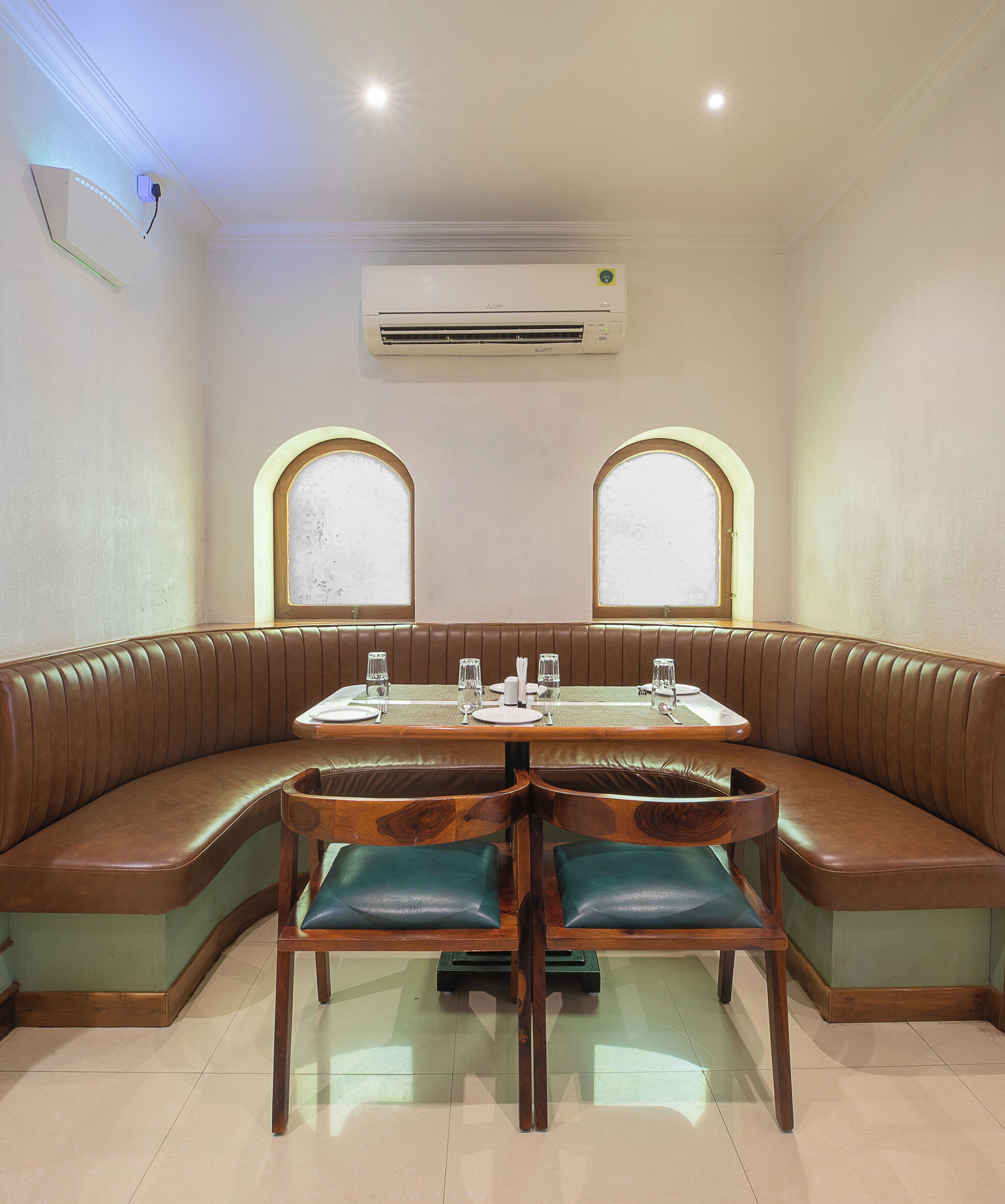 Un restaurante con mesas tipo cabina, una mesa central para comer y un equipo de aire acondicionado en la pared.