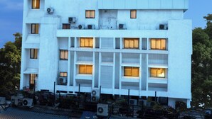 Un hotel con un letrero llamativo, varias ventanas y unidades de aire acondicionado.