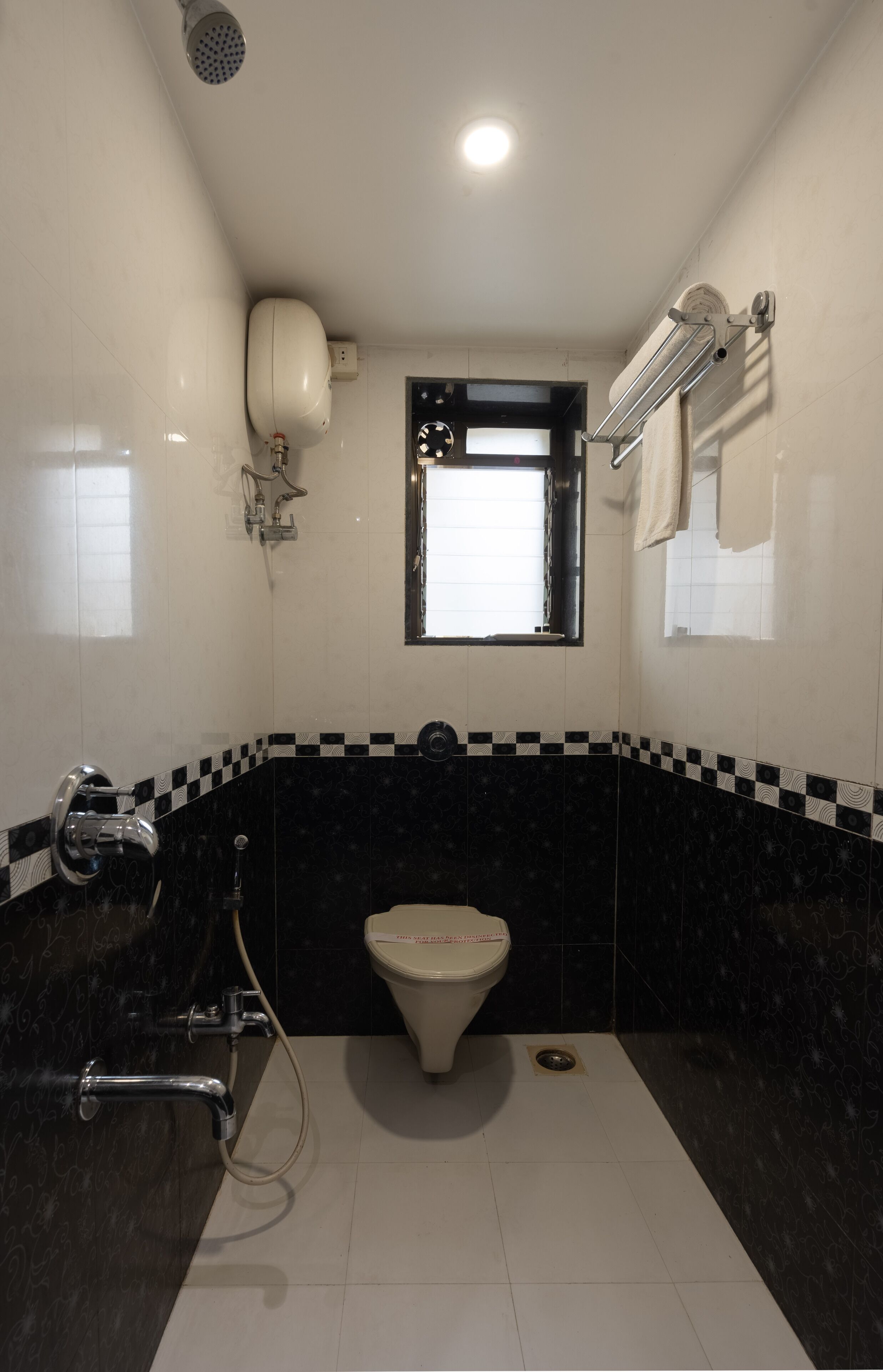 A bathroom with a toilet, a shower, and a window.