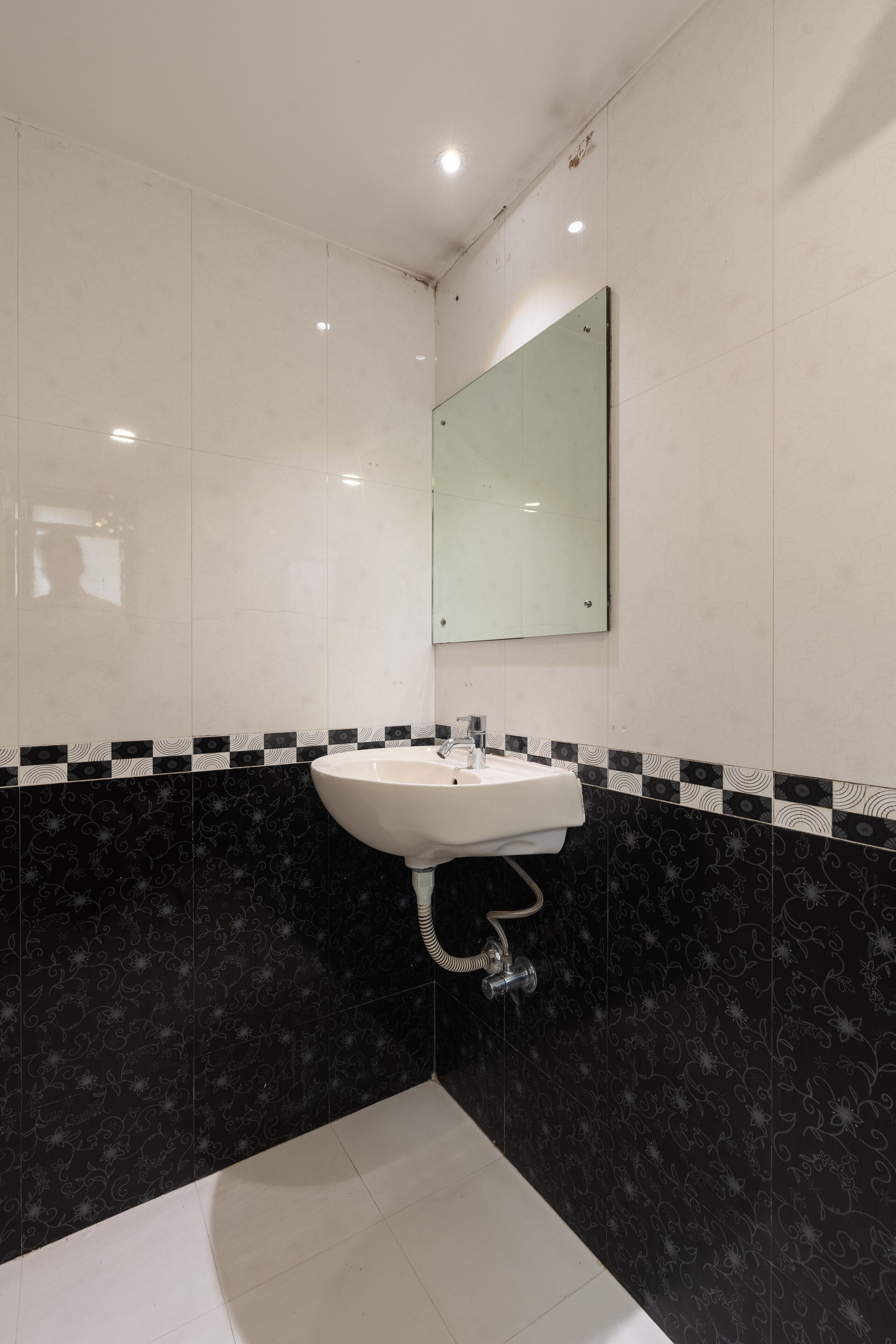 A bathroom with a white sink, black patterned tiles, and a mirror.