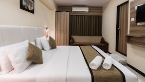 Habitación de hotel con cama, sofá, televisión y aire acondicionado.