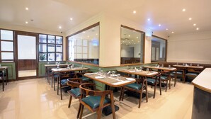 Un restaurante con varias mesas y cabinas, muebles de madera y un espejo grande en la pared.