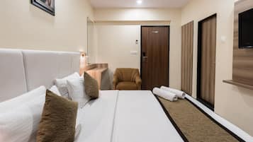 Habitación de hotel con una cama grande, una silla, un armario de madera y un televisor.