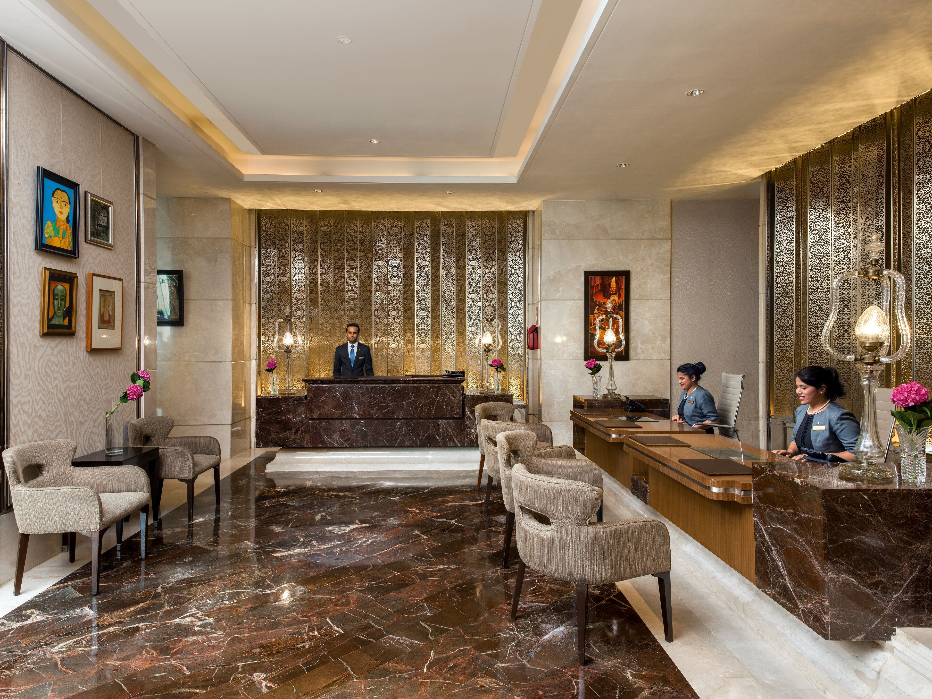 A hotel reception area with a marble floor, a reception desk, and two receptionists.