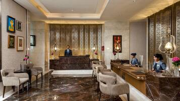 A hotel reception area with a marble floor, a reception desk, and two receptionists.