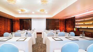 A conference room with white tables, chairs, and a projector screen.