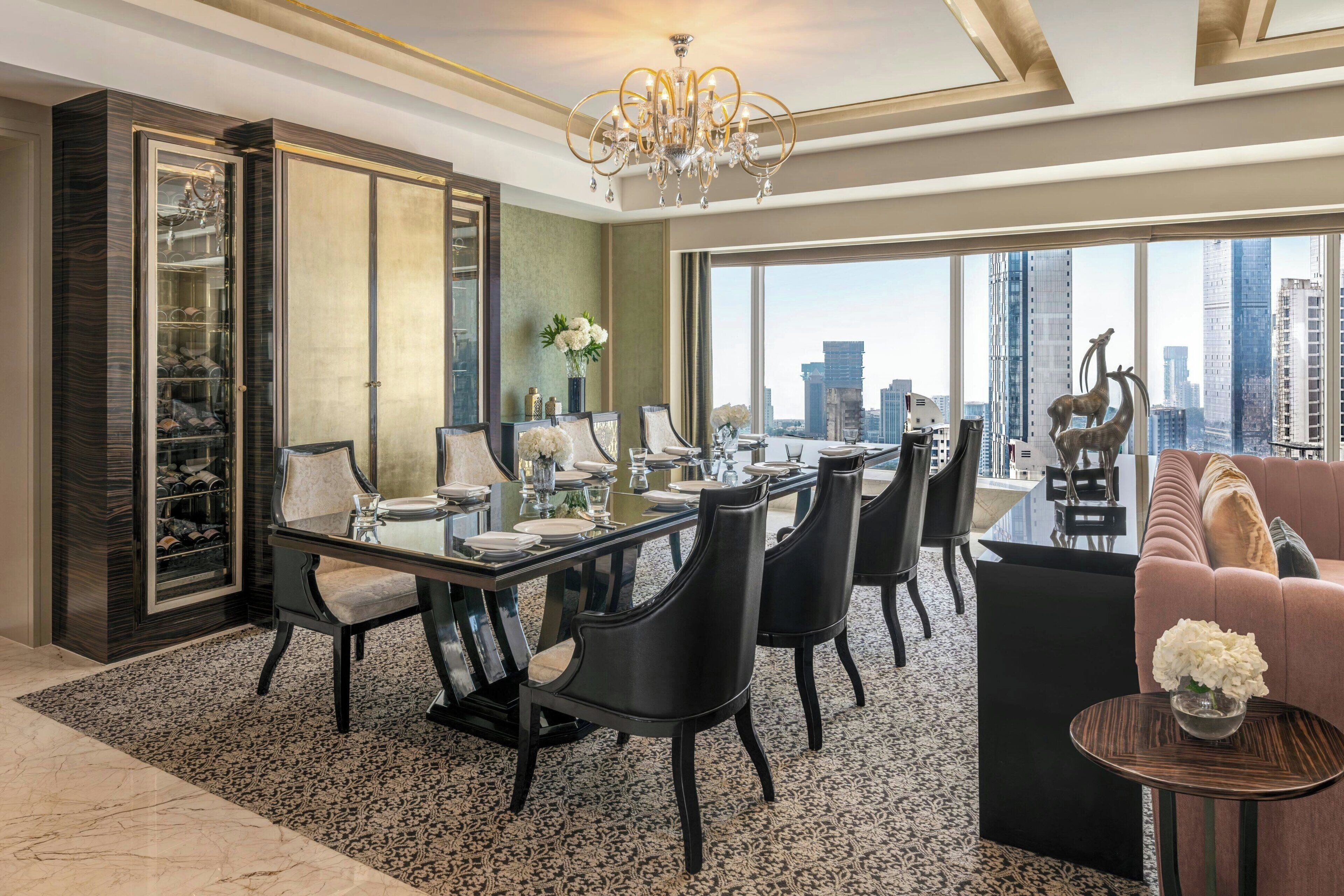 A spacious dining area with a city view, a chandelier, and a wine rack.