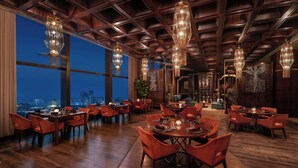 Un comedor amplio con techos altos y ventanas grandes que dan a una vista panorámica de la ciudad.