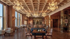 Un vestíbulo amplio con techos altos, candelabros ornamentales y una zona de estar central con sofás y sillones.