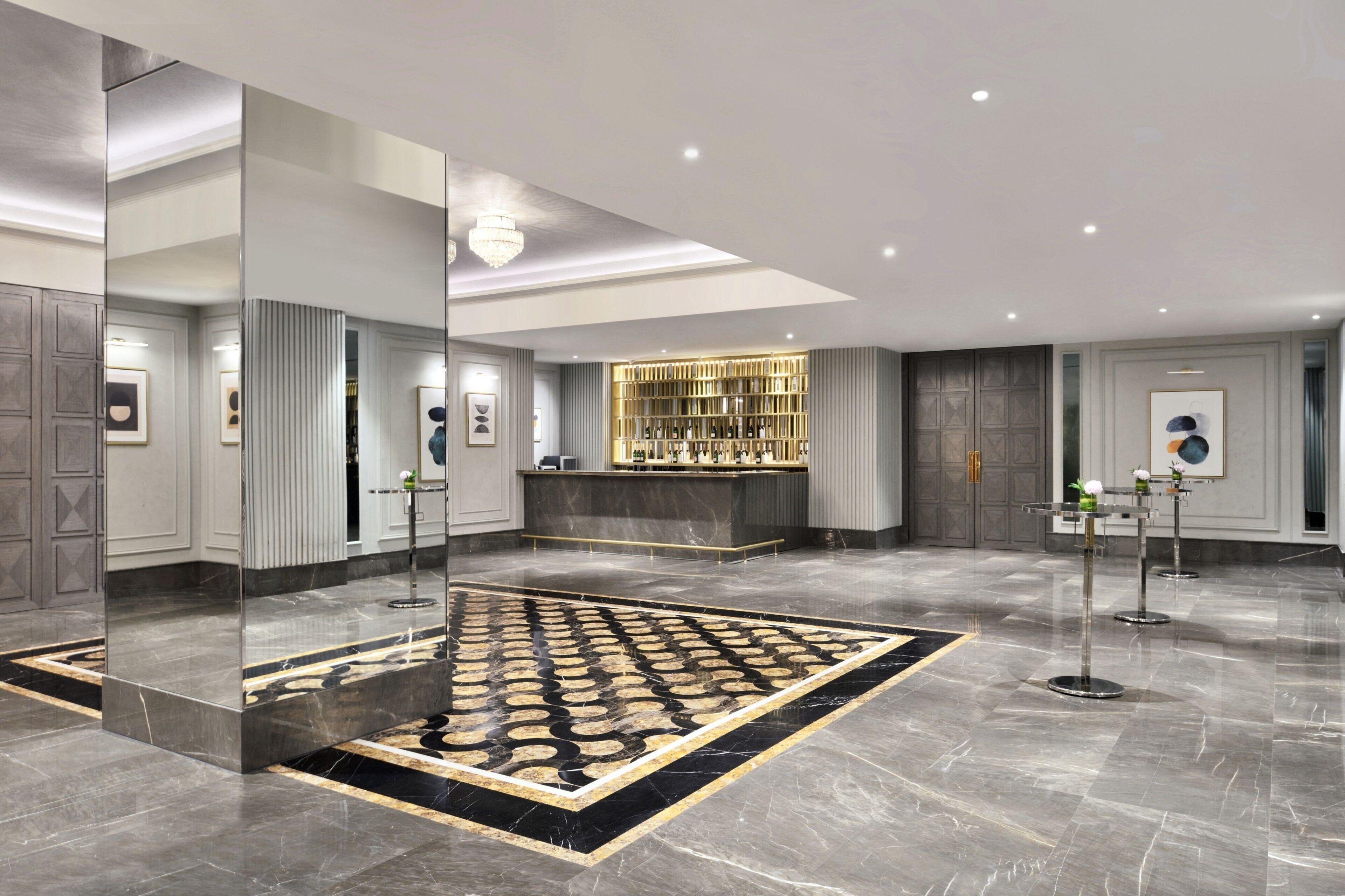 A modern lobby with a marble floor, a reception desk, and a bar area.