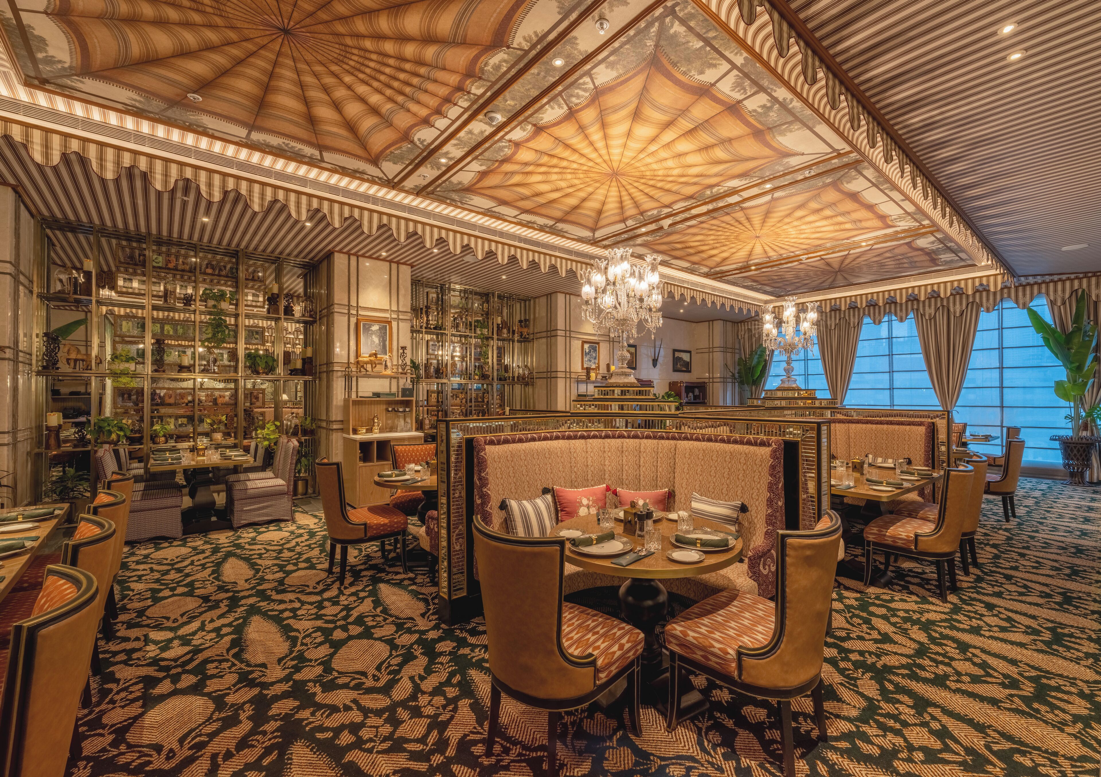 A luxurious interior with a high ceiling, ornate ceiling design, and a seating area with a patterned carpet.