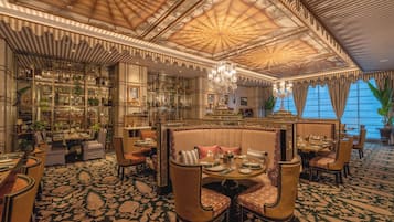 A luxurious interior with a high ceiling, ornate ceiling design, and a seating area with a patterned carpet.