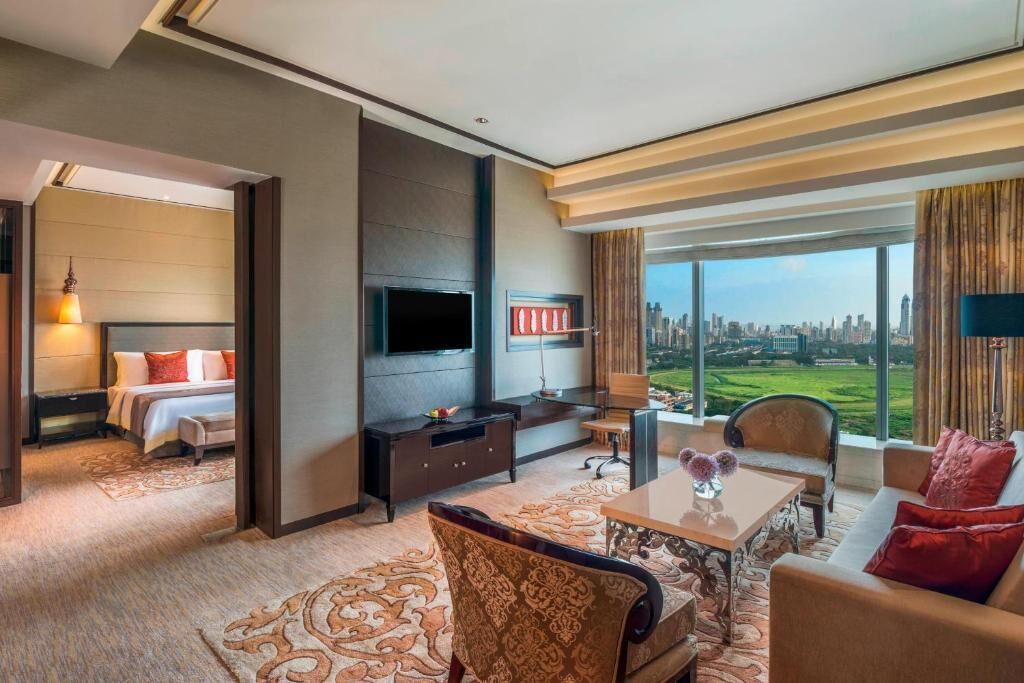 Un cuarto de hotel con cama, televisión, escritorio y vista a la ciudad.