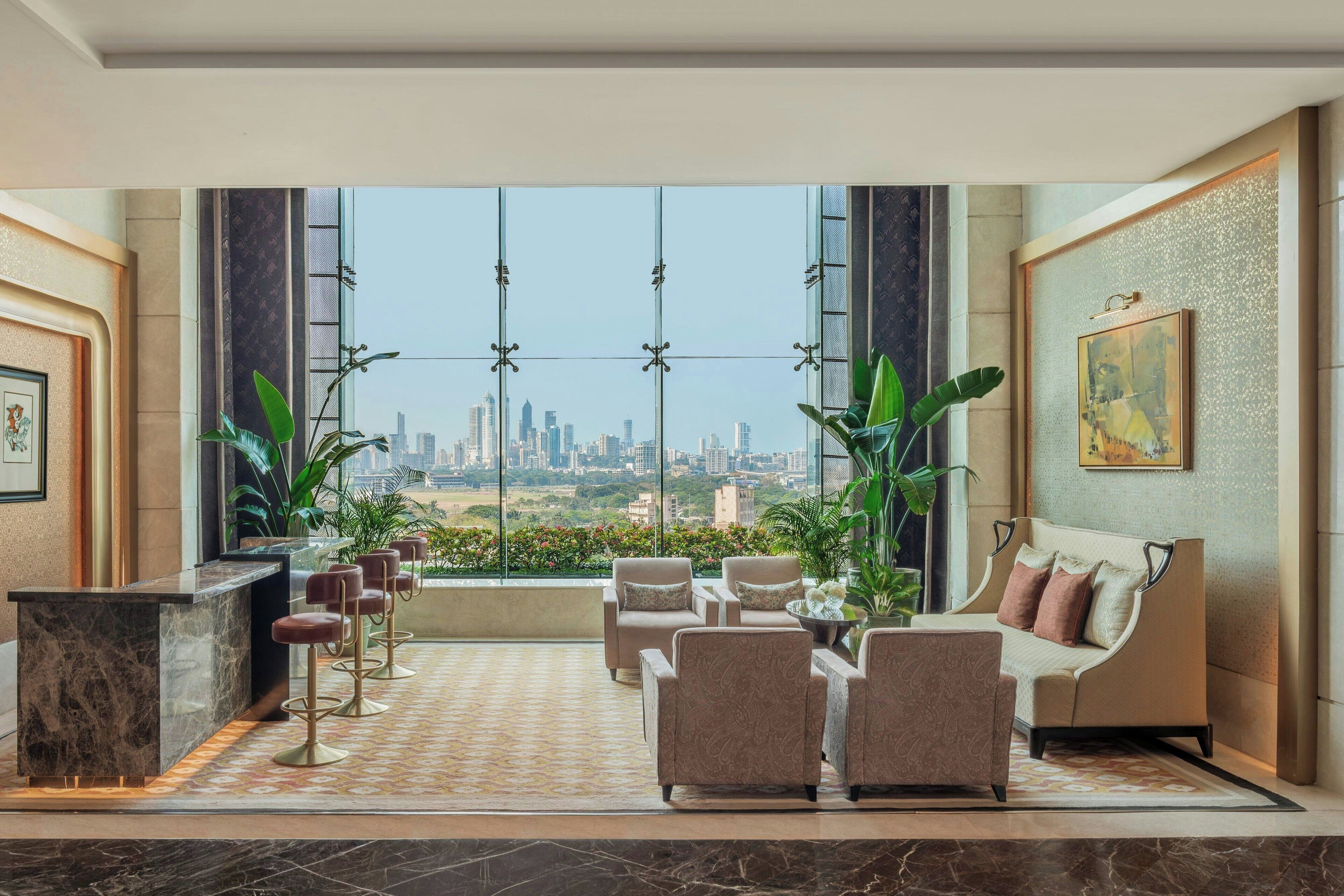 A spacious lobby with a city view, a reception desk, seating area, and a large window.
