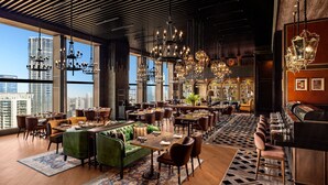 Un restaurante espacioso con techos altos, varios candelabros y vistas a la ciudad.
