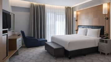 Une chambre d’hôtel équipée d’un lit, d’un bureau, d’une chaise, d’une télévision et d’une table de chevet.