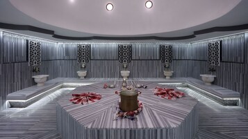 Un bagno moderno con un lavabo circolare al centro, più servizi igienici e pannelli decorativi a parete.