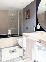 Un bagno moderno con doccia vetrata, vasca da bagno indipendente, water e mobile lavabo con uno specchio grande.