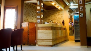 Un espace d’accueil avec un comptoir, des chaises et un mur décoré de motifs.