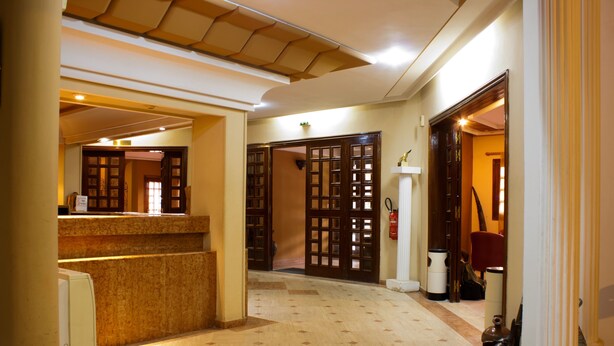 Un hall d’hôtel comprenant un comptoir d’accueil, un extincteur et un escalier menant à un autre étage.
