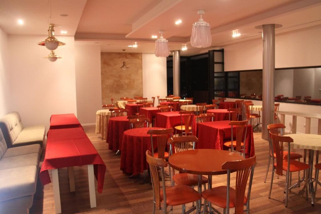 Un restaurante con varias mesas y sillas, una barra larga y lámparas colgantes.