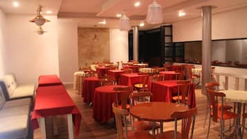 Un restaurante con varias mesas y sillas, una barra larga y lámparas colgantes.