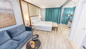 Una habitación de hotel con una cama, un sofá, una pequeña mesa con fruta y un espejo.