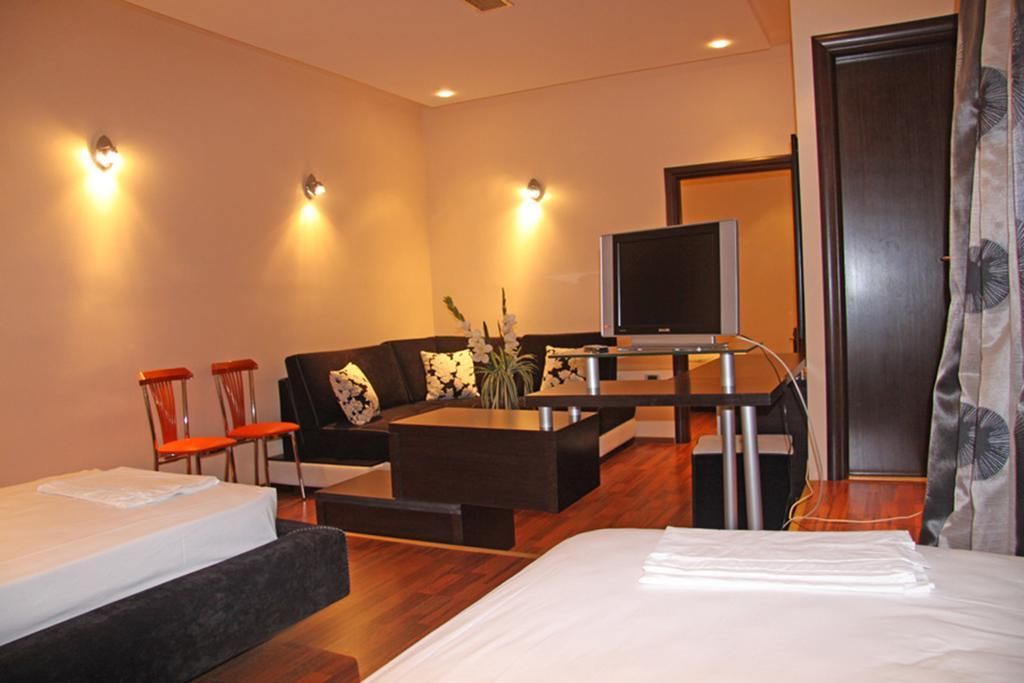 Una habitación de hotel moderna con sofá, televisor pequeño, mesa de centro y cama.