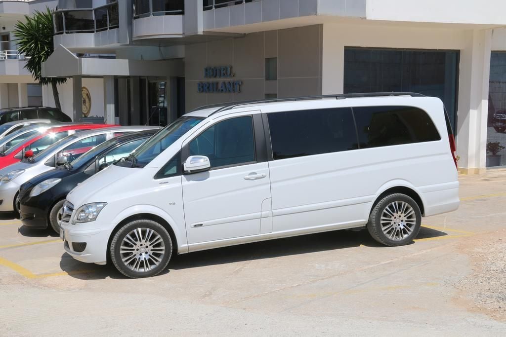 A white minivan parked in a hotel parking lot.