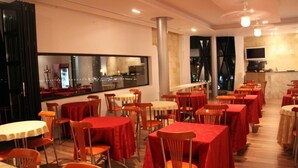 Un restaurante con varias mesas y sillas, un ventanal con vista a la ciudad y un televisor montado en la pared.