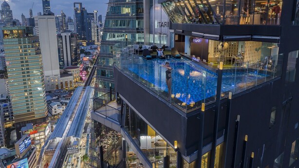A high-rise building with a rooftop infinity pool, glass railings, and a view of the cityscape. - Montraj Continent Sukhumvit Bangkok (Bangkok)