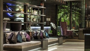 A modern lobby with a seating area, a reception desk, and a large window with a view of greenery. - Montraj Continent Sukhumvit Bangkok (Bangkok)