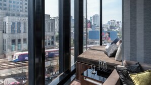 A modern living room with a large window, a sofa, and a coffee table with glasses. - Montraj Continent Sukhumvit Bangkok (Bangkok)